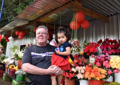 Man and small girl smiling next to flowers for sale