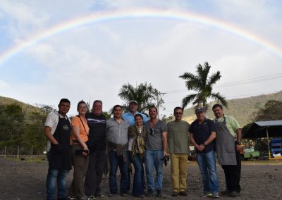 group photo with mountains and full rainbow in background